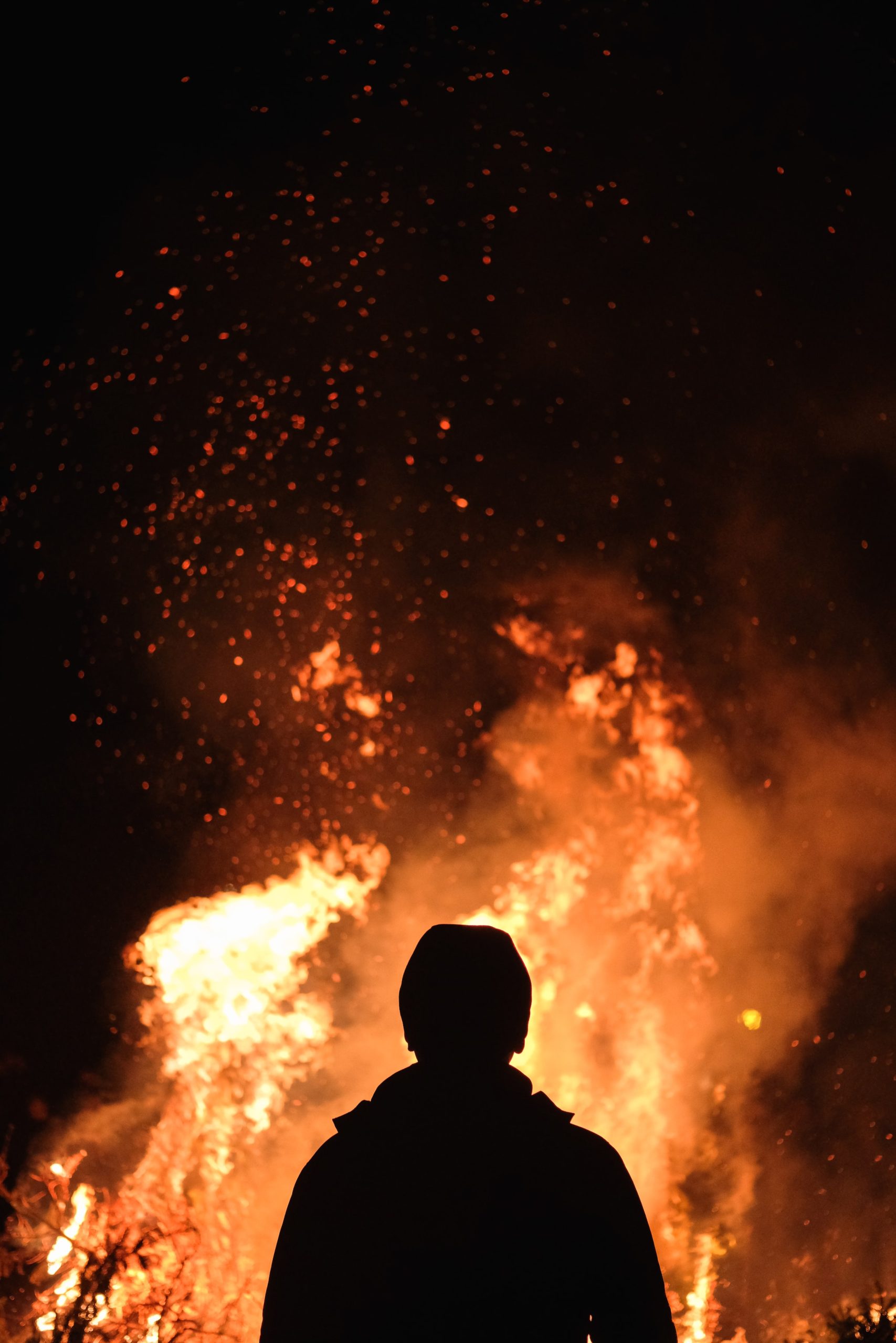Person standing in front of a fire. Photo by Adam Wilson via Unsplash.